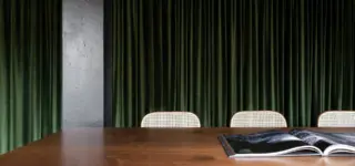 Een houten vergadertafel met een open boek voor groene fluwelen gordijnen in het kantoor van Ninja Theory.