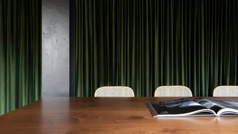 Een houten vergadertafel met een open boek voor groene fluwelen gordijnen in het kantoor van Ninja Theory.